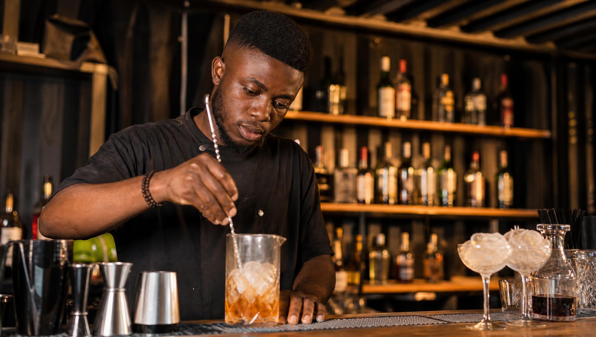 Friends toasting matte black cocktail cans at golden hour in Accra